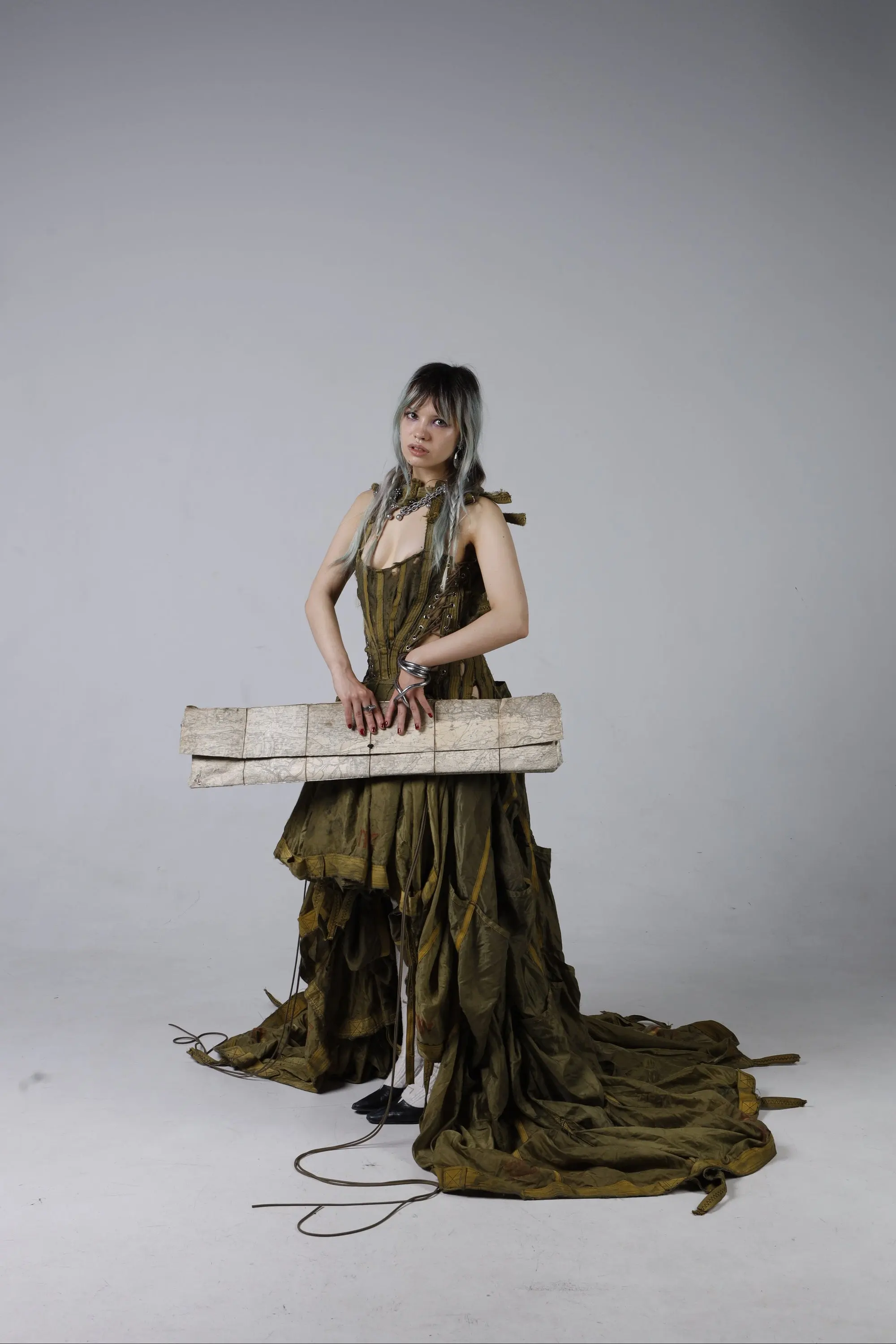 Parachute Dress by GÖRE — full-length front view of the corseted gown made from a Bundeswehr parachute, model holding the Bavaria map clutch
